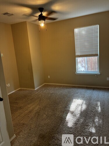 A room with a ceiling fan and a window with blinds.