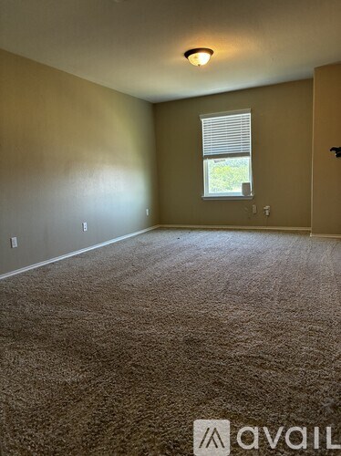 A room with a carpeted floor and a window with blinds.