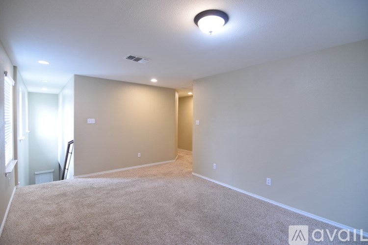 A room with a carpeted floor and a ceiling fan.