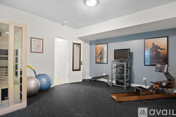 A room with a blue wall and a wooden floor with a gym set up.