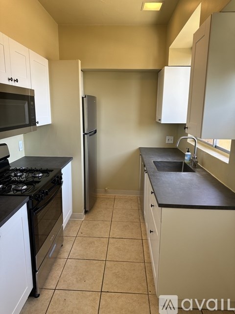 A kitchen with a black stove top and white cabinets.