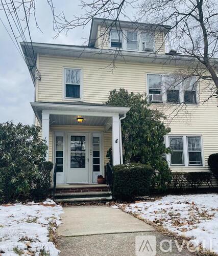 A two-story house with a white front door and steps leading to the entrance.