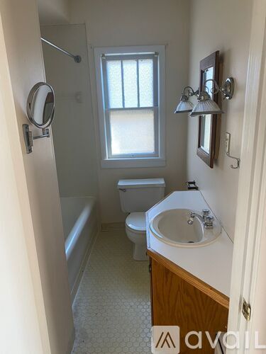 A bathroom with a toilet, sink, and mirror.
