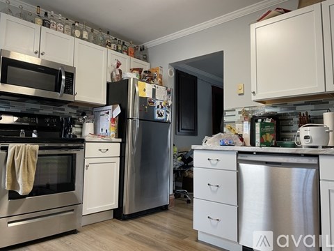 A kitchen with white cabinets and a stainless steel refrigerator.
