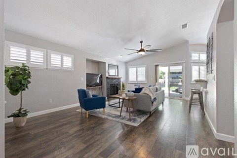 A living room with a blue chair and a ceiling fan.
