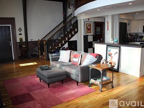 A living room with a grey couch and a red rug.