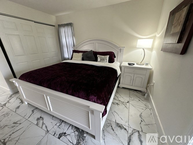 A bedroom with a white bed and a marble floor.