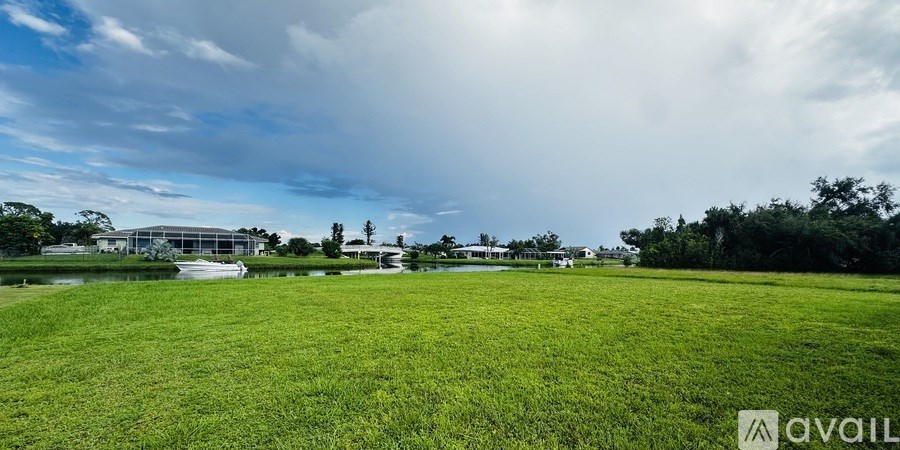 A grassy field with a building in the distance and a cloudy sky above.