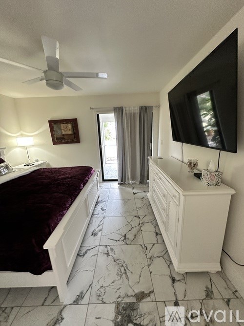 A bedroom with a marble floor and a white ceiling fan.