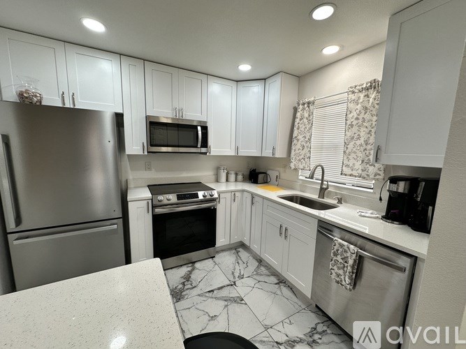 A kitchen with a marble countertop and stainless steel appliances.