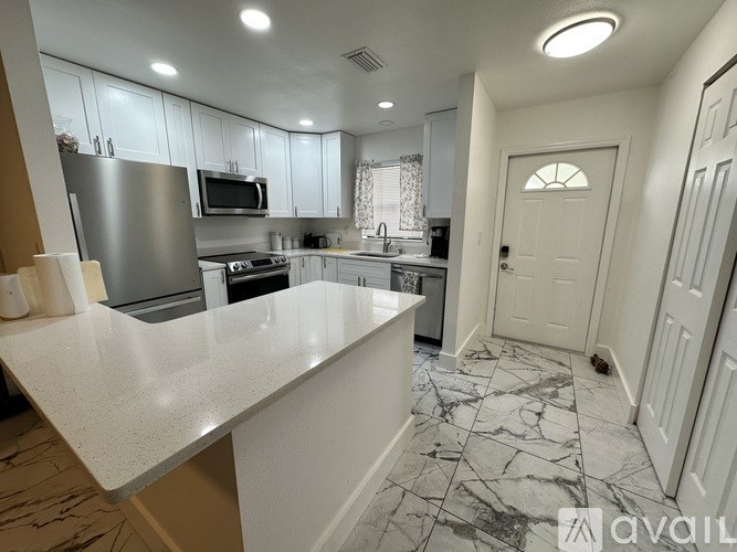 A kitchen with a marble floor and white cabinets.