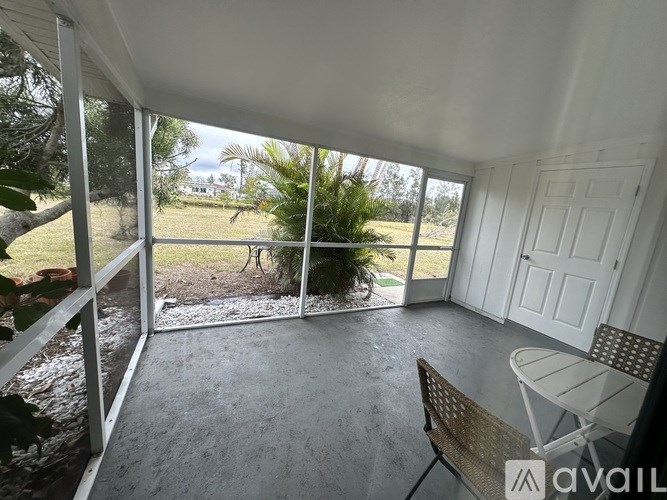 A patio with a table and chairs overlooks a grassy area.
