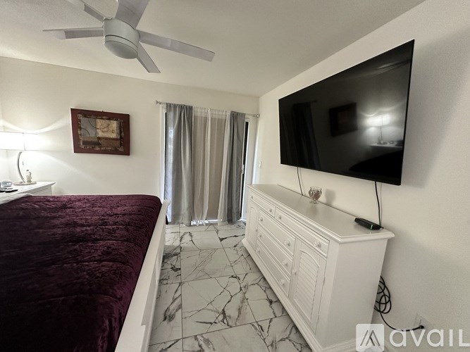 A bedroom with a bed, a dresser, and a television.