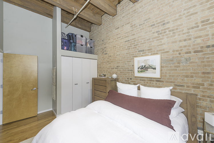 A bedroom with a white bed and a brick wall.