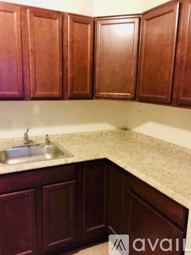 A kitchen with brown cabinets and a marble countertop.