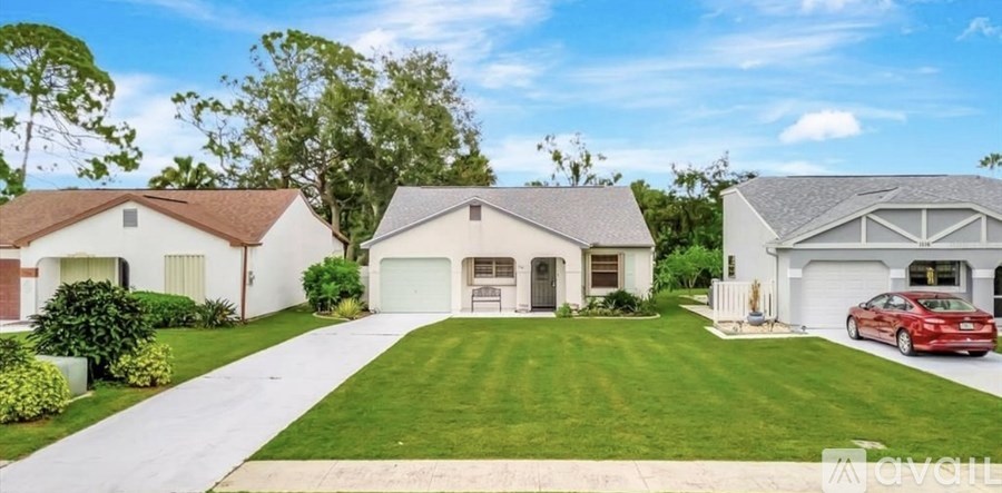 A red car is parked in front of a white garage.