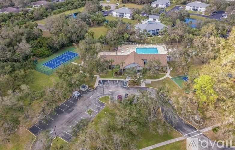 A bird's eye view of a residential area with a tennis court, swimming pool, and parking lot.