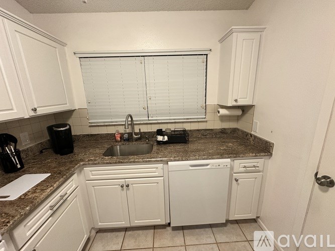 A kitchen with white cabinets and a granite countertop.