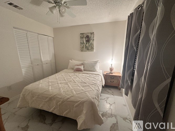 A bedroom with a large bed and a ceiling fan.