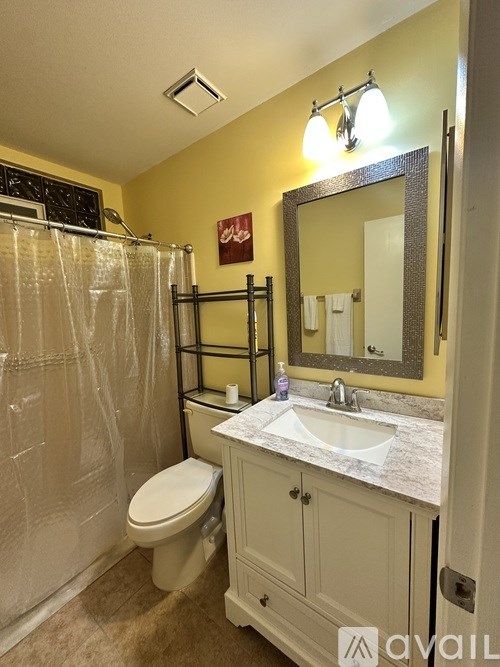 A bathroom with a toilet, sink, and mirror.