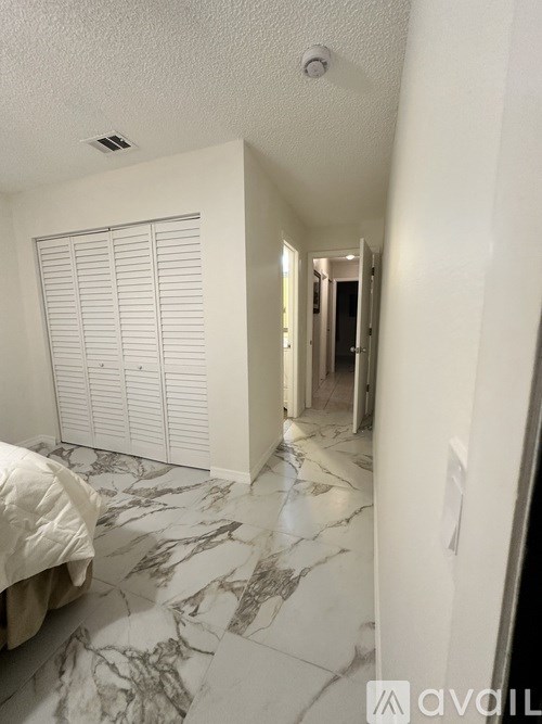 A bedroom with a marble floor and white walls.