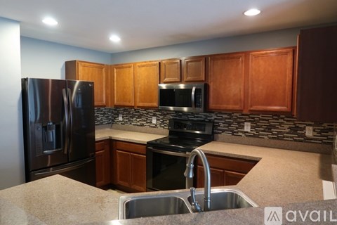 A kitchen with wooden cabinets and a black refrigerator.