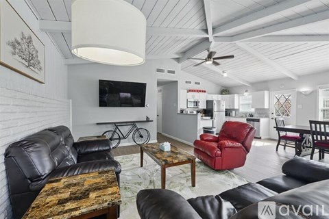 A living room with a black leather couch and a wooden coffee table.