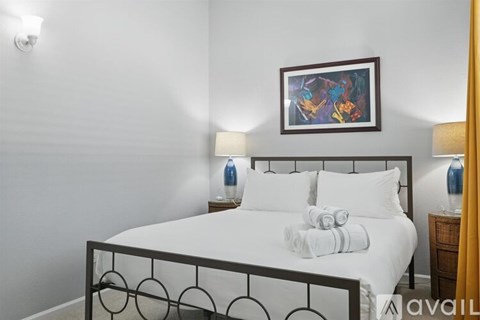 A bedroom with a white bed and a picture frame on the wall.