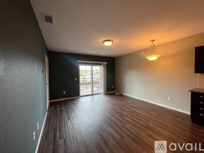A spacious room with dark wood flooring and a large window.