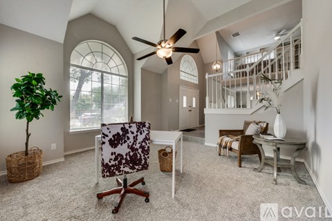 A living room with a ceiling fan and a chair with a floral pattern.