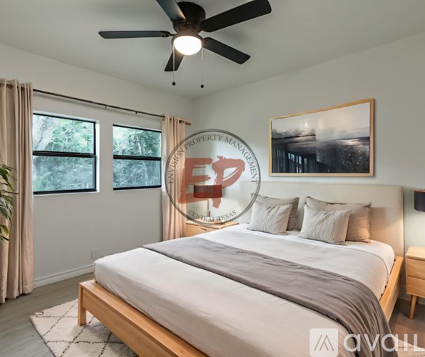 A bedroom with a bed, a ceiling fan, and a window with curtains.