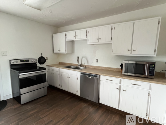 A kitchen with white cabinets and wooden floors.