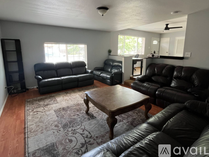 A living room with black leather furniture and a rug.