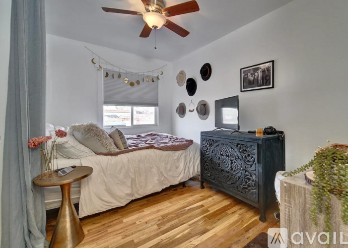 A bedroom with a bed, a dresser, and a ceiling fan.