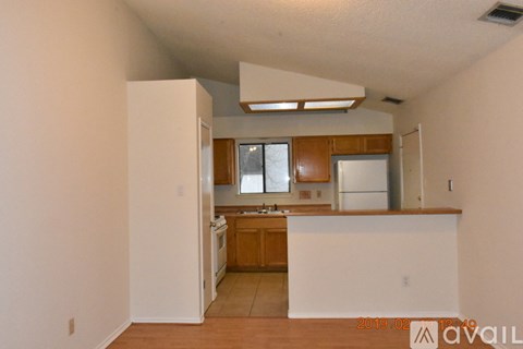 A kitchen with white walls and wooden cabinets is available for rent.