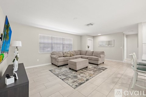 A living room with a grey sofa set and a rug.