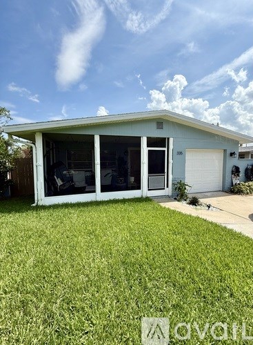 A house with a white garage door and a blue house number sign.