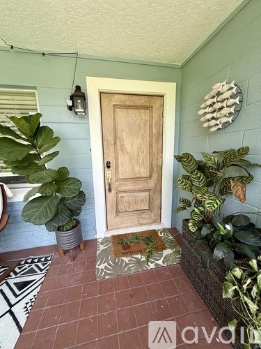 A wooden door is flanked by two potted plants.