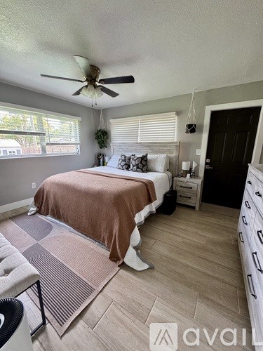 A bedroom with a bed, dresser, and ceiling fan.