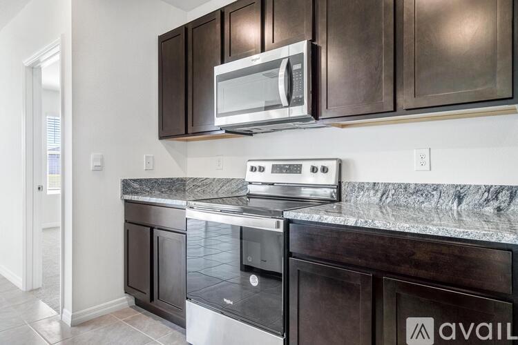 A kitchen with dark brown cabinets and a granite countertop.