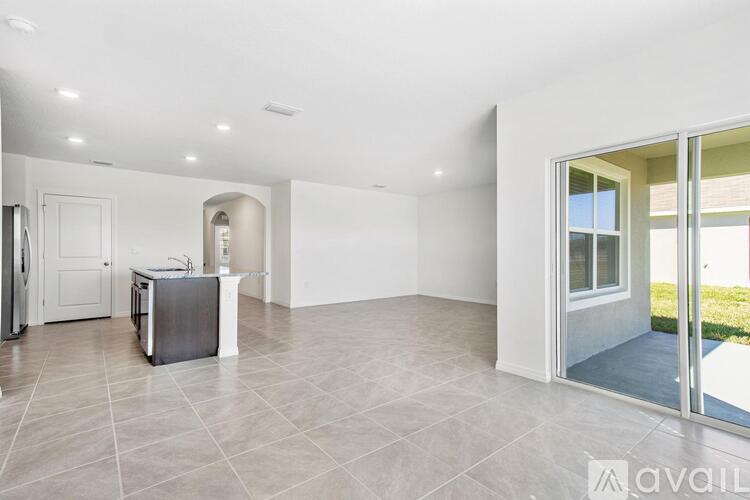 A spacious room with a television and a sliding glass door leading to a balcony.