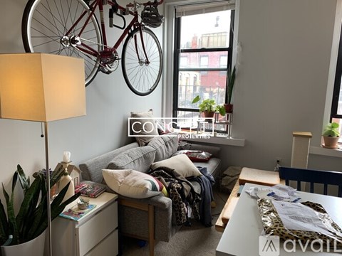 A living room with a bicycle hanging on the wall and a couch with pillows.