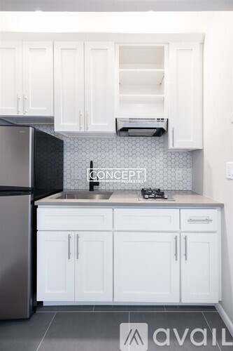 A kitchen with white cabinets and a black refrigerator.
