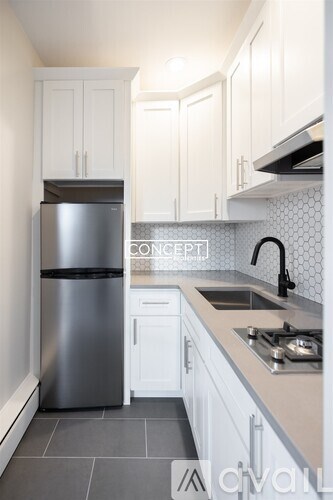 A modern kitchen with a stainless steel refrigerator and white cabinets.