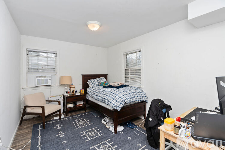 A bedroom with a bed, chair, and desk.