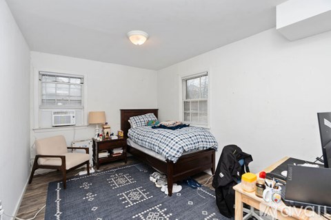 A bedroom with a bed, chair, and desk.
