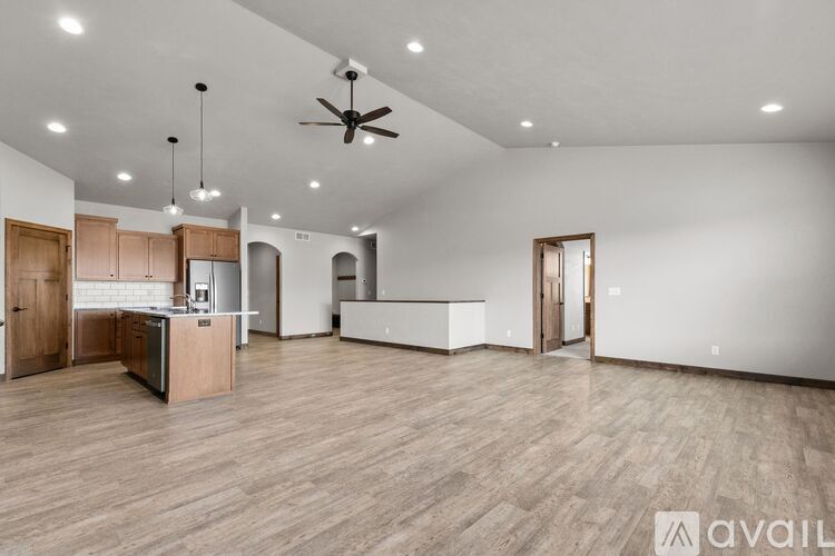A spacious, empty room with wooden floors and a ceiling fan.