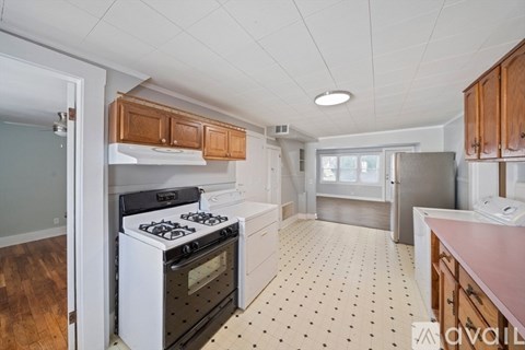 A kitchen with a white stove top oven and wooden cabinets.