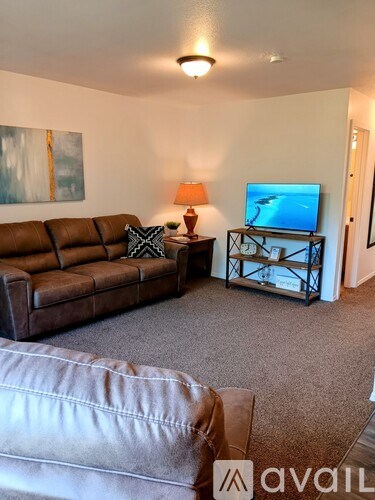 A living room with a brown leather couch and a television on a stand.