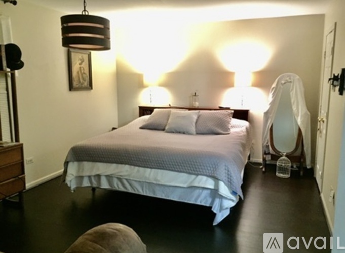 A bedroom with a bed, a dresser, and a lamp.